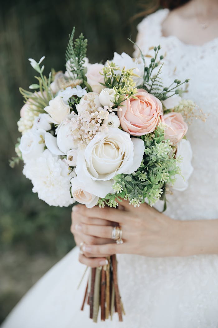 Close-up of a bride holding a delicate bouquet of roses and greenery, perfect for weddings.
