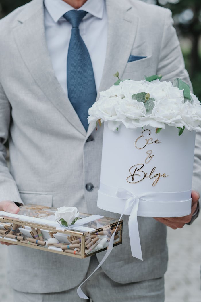 Man in suit holding a wedding gift box with flowers, perfect for elegant celebrations.