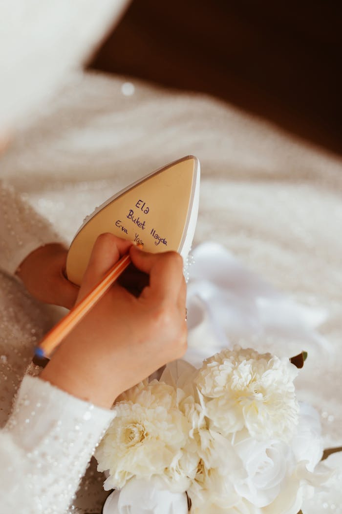 Bride writes heartfelt message on shoe sole amidst delicate white flowers.