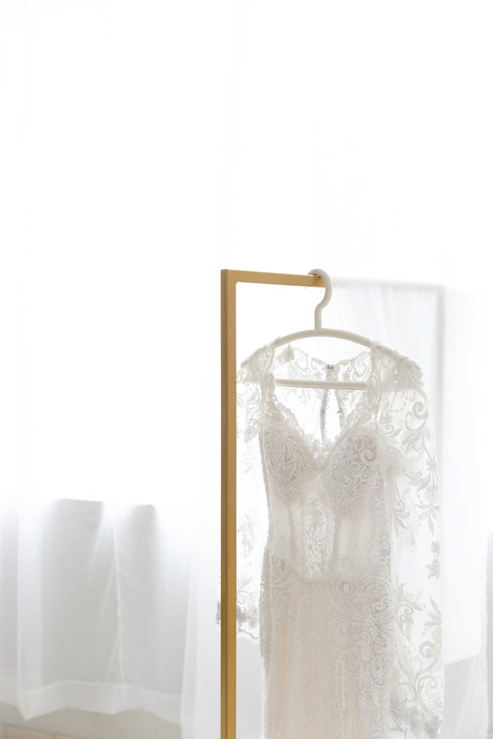 Beautiful lace wedding dress hanging indoors with soft light in São Paulo, ideal for bridal themes.